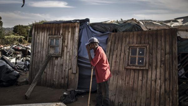 A resident of Plot 323 in Wilgespruit, Johannesburg, pauses on May 08, 2020 in front of a wooden shack during a ministerial visit aimed to ensure that the vulnerable residents of the informal settlement are soon properly accommodated in temporary residential units. MARCO LONGARI / AFP
