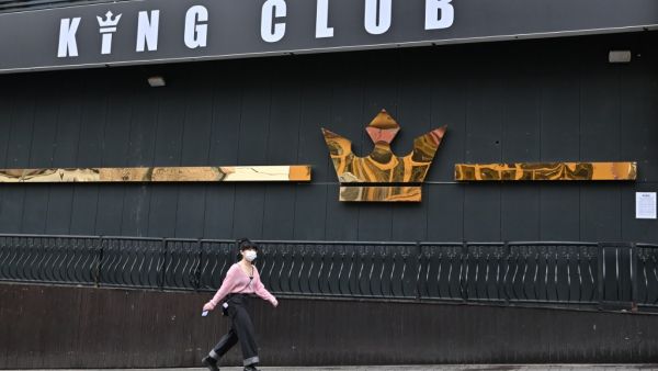 A woman wearing a face mask walks past a night club, now closed following a visit by a confirmed COVID-19 coronavirus coronavirus patient, in the popular nightlife district of Itaewon in Seoul on May 10, 2020. South Korea's capital has ordered the closure of all clubs and bars after a burst of new cases sparked fears of a second coronavirus wave as President Moon Jae-in urged the public to remain vigilant. Jung Yeon-je / AFP