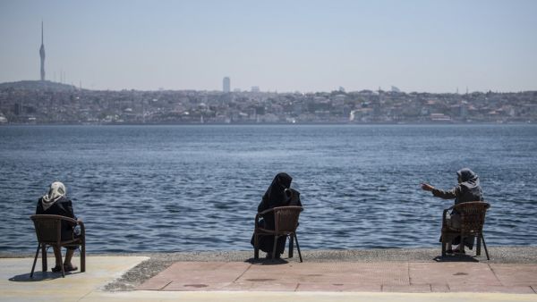 Women wearing protective face masks, sit apart following social distancing measures at the seaside on May 10, 2020, at Kabatas in Istanbul, after a month and a half of lockdown restrictions aimed at stemming the spread of the novel coronavirus, COVID-19. Turkish people aged 65 and over on May 10, 2020, described their joy after the government allowed them to go outside for the first time in nearly two months in an easing of the coronavirus restrictions. While 24 provinces including Ankara and Istanbul are s