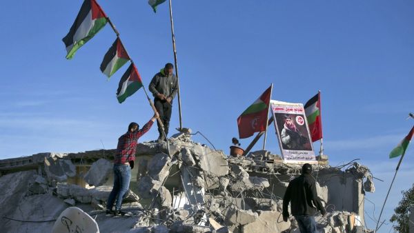 Palestinian men place a picture of Palestinian assailant Qassam Barghouti on the rublle of his family house after it was partially demolished by Israeli forces in the village of Kobar, near Ramallah, in the Israeli-occupied West Bank on May 11, 2020. Israeli forces demolished the home of a Palestinian accused of involvement in a bomb attack last year that killed an Israeli teenager in the occupied West Bank. The explosion on August 23, 2019, near a spring close to the Jewish settlement of Dolev, killed 17-y