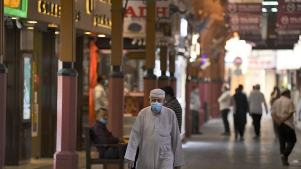 en wearing face masks, due to the COVID-19 coronavirus pandemic, walk past jewellers' shops at the Dubai Gold Souk in the Gulf emirate on May 13, 2020, as markets re-open amidst an easing of pandemic restrictions. (AFP)