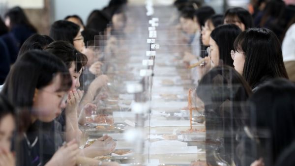 Students sit behind protective screens as a preventative measure against the COVID-19 novel coronavirus as they eat lunch at a high school in Daejeon on May 20, 2020. Hundreds of thousands of South Korean students returned to school on May 20 as education establishments started reopening after a coronavirus delay of more than two months.  Yonhap / AFP