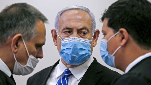 Israeli Prime Minister Benjamin Netanyahu (C), wearing a protective face maks, speaks with his lawyer inside a courtroom at the district court of Jerusalem on May 24, 2020, during the first day of his corruption trial. Fresh from forming a new government after more than 500 days of electoral deadlock, Netanyahu is expected to begin a new battle in the Jerusalem District Court -- to stay out of prison. The 70-year-old was scheduled to appear at a court hearing to formally confirm his identity to judges, afte