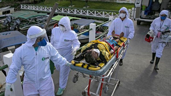 Health personnel of a medical emergency response service carry Brazilian Eladio Lopes, 79, -infected with the new coronavirus- on a stretcher to be transferred on an ambulance boat from the community of Portel to a hospital in Breves, on Marajo island, Para state, Brazil, on May 25, 2020. Ambulance boat services allow critical COVID-19 patients to be tranferred in very remote areas surrounded by water in Brazil. TARSO SARRAF / AFP
