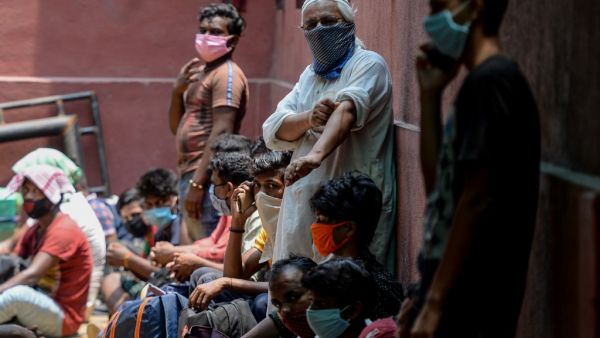 Migrant workers and families gather in front of a police station to get transferred to a railway station to board a special train to Bihar state after the government eased a nationwide lockdown imposed as a preventive measure against the COVID-19 coronavirus, in Chennai on May 27, 2020. Arun SANKAR / AFP