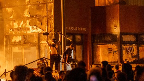 Flames from a nearby fire illuminate protesters standing on a barricade in front of the Third Police Precinct on May 28, 2020 in Minneapolis, Minnesota, during a protest over the death of George Floyd, an unarmed black man, who died after a police officer kneeled on his neck for several minutes. (AFP/File)