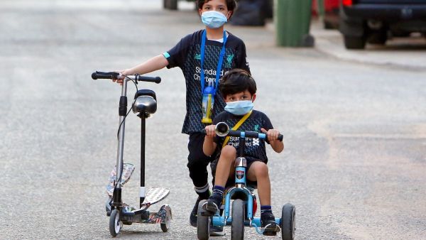 Kuwaiti children, wearing protective facemasks due to the coronavirus pandemic, cycle in a street in the Salwa district of Kuwait City on May 29, 2020. YASSER AL-ZAYYAT / AFP