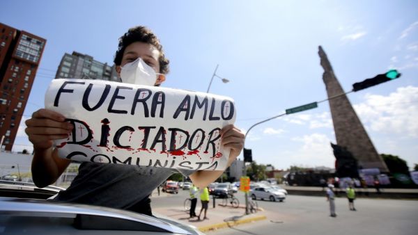 A demonstrator displays a sign reading "AMLO Out. Communist Dictator" during a caravan to protest against the government of Mexican President Andres Manuel Lopez Obrador (ALMO) and his handling of the COVID-19 novel coronavirus pandemic, in Guadalajara, Jalisco State, Mexico, on May 30, 2020. Ulises Ruiz / AFP