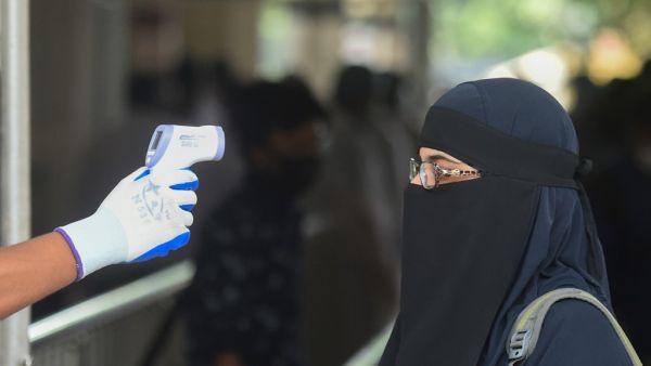 A railway official checks the temperature of a woman queueing to enter the Kamalapur railway station after the government-imposed lockdown as a preventive measure against the COVID-19 coronavirus ended, in Dhaka on May 31, 2020. Munir UZ ZAMAN / AFP