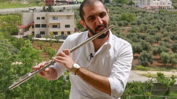 Ebaa Akroush, a 24-year-old Jordanian music graduate from the University of Jordan and first-prize winner of a culture ministry talent contest, plays the flute on his balcony in Fuheis town, around 20 kilometres northwest of the capital Amman, on April 27, 2020. (Photo by Khalil MAZRAAWI / AFP)
