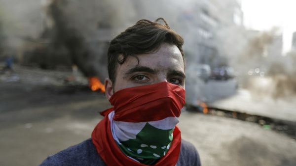 A Lebanese protester stands in front of burning tyres and debris in the area of Jal el-Dib, on the northern outskirts of the Lebanese capital Beirut, on November 13, 2019. A man was shot dead south of Beirut after the army opened fire to disperse protesters blocking roads, Lebanese state media said, nearly a month into an unprecedented anti-graft street movement. JOSEPH EID / AFP