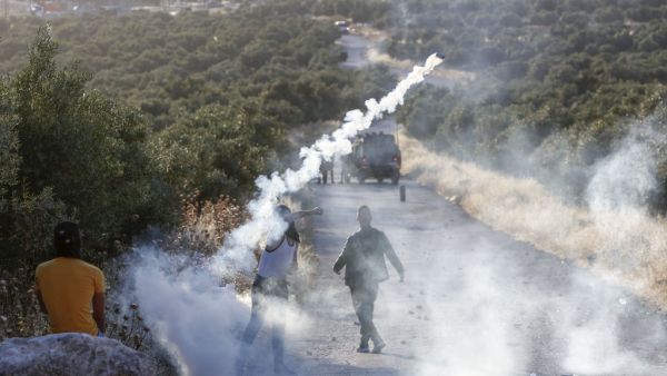 A Palestinian demonstrator returns a tear gas canister during clashes with Israeli soldiers in the town of Tuqua in the Israeli-occupied West Bank on May 28, 2020. Musa Al SHAER / AFP