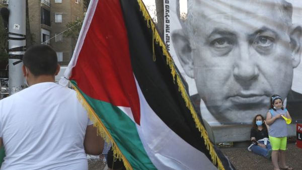 A protester carries the Palestinian flag during a demonstration in Tel Aviv's Rabin Square on June 6, 2020, to denounce Israel's plan to annex parts of the occupied West Bank. Israeli Prime Minister Benjamin Netanyahu has vowed to forge ahead with annexing settlements and the Jordan Valley, in line with the peace proposals unveiled in January by US President Donald Trump. The plan has been angrily rejected by the Palestinians, who say they were not consulted on proposals they see as capitulating to Israeli 