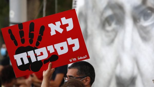 Protesters carry a placard which reads in hebrew "no to annexation" as they gather in Tel Aviv's Rabin Square on June 6, 2020, to denounce Israel's plan to annex parts of the occupied West Bank. Israeli Prime Minister Benjamin Netanyahu has vowed to forge ahead with annexing settlements and the Jordan Valley, in line with the peace proposals unveiled in January by US President Donald Trump. The plan has been angrily rejected by the Palestinians, who say they were not consulted on proposals they see as capit