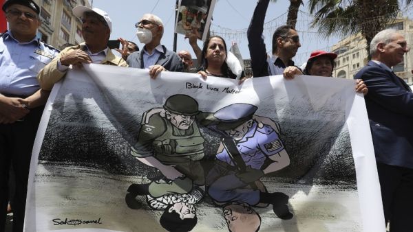 Palestinian demonstrators take part in a demonstration against police brutality and in support of US protesters over the death George Floyd, an unarmed black man who died after a white policeman knelt on his neck during an arrest in the US, in the centre of the occupied West Bank city of Ramallah on June 8, 2020. ABBAS MOMANI / AFP