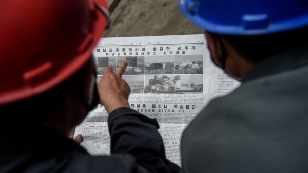 Employees of the Kim Jong Thae Electric Locomotive Complex in Pyongyang read a copy of the Rodong Sinmun newspaper showing coverage of North Korea's demolition of the north-south joint liaison office, on June 17, 2020. North Korea's spectacular destruction of its liaison office with the South is part of a series of staged provocations aimed at forcing concessions from Seoul and Washington, analysts say. KIM Won Jin / AFP