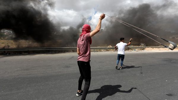 A Palestinian demonstrator uses a slingshot to hurl rocks at Israeli troops during a protest against Israel's plan to annex parts of the occupied West Bank, near the city of Ramallah, on June 19, 2020. Israel intends to annex West Bank settlements and the Jordan Valley, as proposed by US President Donald Trump, with initial steps slated to begin from July 1. ABBAS MOMANI / AFP
