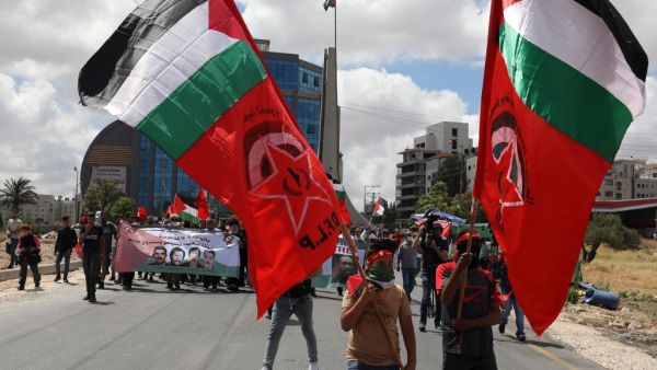 Palestinian demonstrators carry flags during a protest against Israel's plan to annex parts of the occupied West Bank, near the city of Ramallah, on June 19, 2020. Israel intends to annex West Bank settlements and the Jordan Valley, as proposed by US President Donald Trump, with initial steps slated to begin from July 1. ABBAS MOMANI / AFP