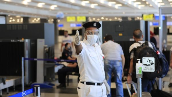 An Egyptian policeman, wearing a protective face shield, signals to passengers at the Sharm el-Sheikh international airport on June 20, 2020. Khaled DESOUKI / AFP