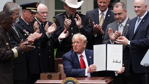 Surrounded by members of law enforcement, U.S. President Donald Trump holds up an executive order he signed on Safe Policing for Safe Communities during an event in the Rose Garden at the White House June 16, 2020 in Washington, DC. President Trump signed an executive order on police reform amid the growing calls after the death of George Floyd. Alex Wong/Getty Images/AFP ALEX WONG / GETTY IMAGES NORTH AMERICA / Getty Images via AFP