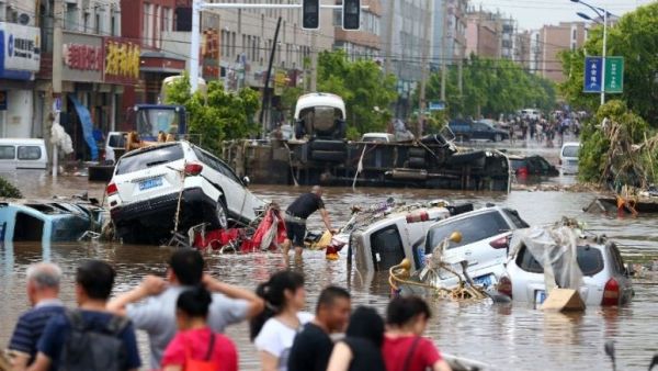 Residents look towards submerged cars in a flooded street in Yongji, a county under the administration of the city of Jilin in northeast China's Jilin province on July 14, 2017. Photo: STR/AFP
