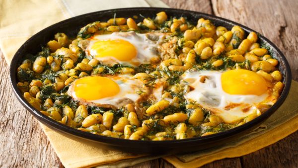 Traditional Iranian cuisine Baghali Ghatogh beans and dill with fried eggs, garlic and turmeric close-up in a frying pan on a table  (Shutterstock)	