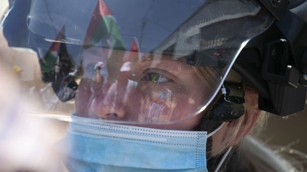 A Palestinian flag is reflected on the helmet of an Israeli border guard wearing a mask against Covid-19 as forces keep watch while Palestinians perform Friday prayer during a protest against Israel's plan to annex parts of the occupied West Bank, in the Palestinian village of Haris, southwest of Nablus, on June 26, 2020. JAAFAR ASHTIYEH / AFP