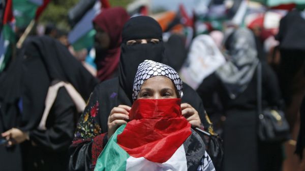 A Palestinian woman fastens a national flag as a mask on the face of a girl during a demonstration against Israel's West Bank annexation plans in Gaza City on July 1, 2020. Expectations of a major Israeli announcement on controversial annexations in the occupied West Bank dimmed, as global criticism of the project mounted and Palestinian protesters began gathering in Gaza. Mohammed ABED / AFP