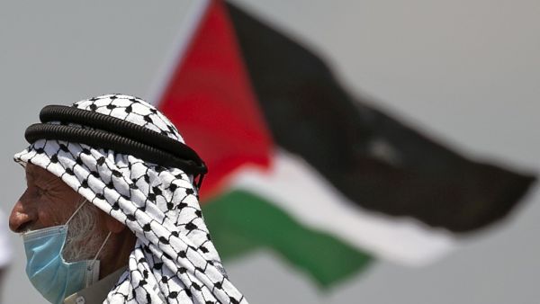 A Palestinian demonstrator waves a national flag during a protest against the expansion of existing Jewish settlements, in the town of Biddya, in the Israeli-occupied West Bank on July 6, 2020. JAAFAR ASHTIYEH / AFP