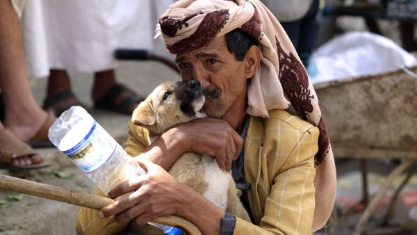 A Yemeni man plays with a puppy in a street in the capital Sanaa, on July, 13, 2020. MOHAMMED HUWAIS / AFP