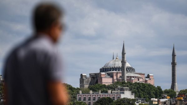 A man stays near the shore of Bosphorus at Karakoy district on July 14, 2020 as Hagia Sophia is seen in the backround in Istanbul. Turkey's Hagia Sophia could open to visitors outside prayer times and its Christian icons will remain, religious officials said on Tuesday, after a court ruling paved the way for it to become a mosque. Ozan KOSE / AFP