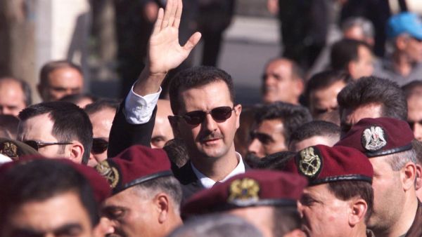 A file photo taken on June 13, 2000 shows Syrian heir apparent Bashar al-Assad waving to supporters as he marches behind the coffin of his father, Syrian President Hafez al-Assad, during his funeral in Damascus. Bashar al-Assad's rise to power after three decades of his father's iron-fisted rule raised hope of democratic opening. But 20 years later, Syria is isolated and war-ravaged. Crumbling under a stinging economic downturn, Western sanctions and nine years of war, Syria today is a far cry from the visi