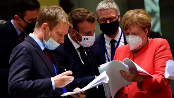 Spain's Prime Minister Pedro Sanchez (L), French President Emmanuel Macron (C) and German Chancellor Angela Merkel (R) look into documents during an EU summit in Brussels on July 20, 2020, as the leaders of the European Union hold their first face-to-face summit over a post-virus economic rescue plan. JOHN THYS / POOL / AFP