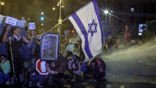 Protesters crouch down as police use water cannons as they clash during demonstrations against the Israeli government near the Prime Minister's residence in Jerusalem on July 25, 2020. AHMAD GHARABLI / AFP