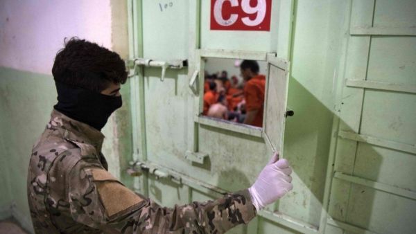 A member of the Syrian Democratic Forces guards IS suspects in north-east Syria. (AFP/GETTY IMAGES)