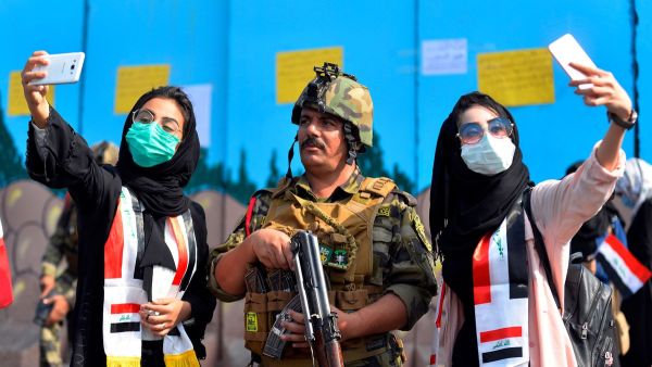 Iraqi students pose for selfies with a member of the security forces during ongoing anti-government protests in the central city of Diwaniyah on October 31, 2019.  (Haidar Hamdani / AFP / Getty)