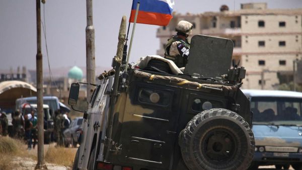A Russian soldier on his armoured vehicle watches Syrian rebels during evacuation from Deraa city, on July 15, 2018. AFP