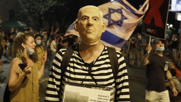 A protester, wearing a mask of Israeli Prime Minister Benjamin Netanyahu, takes part in ongoing anti-government demonstrations in Jerusalem on July 30, 2020. Protests have grown against the veteran premier over his handling of the coronavirus pandemic and the devastating economic crisis it has caused. The prime minister has been accused of leading a chaotic virus containment strategy as cases have surged and economically painful initial restrictions have been reimposed.  Ahmad GHARABLI / AFP