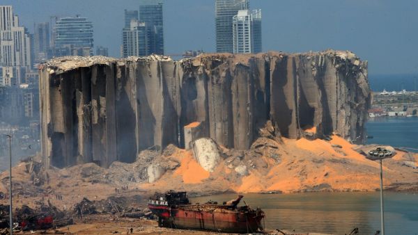 A picture taken on August 5, 2020 shows the damaged grain silo and a burnt boat at Beirut's harbour, one day after a powerful twin explosion tore through Lebanon's capital, resulting from the ignition of a huge depot of ammonium nitrate at the city's main port. STR / AFP
