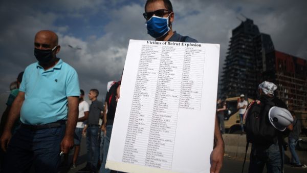 A Lebanese man carries a placard bearing the names of the Beirut port explosion, during a commemoration ceremony across from the capital's harbour, on August 11, 2020. PATRICK BAZ / AFP