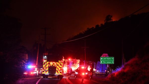 Fire trucks and emergency vehicles huddle on the road as the horizon is set ablaze by the Lake Fire flames in the Angeles National Forest, by Lake Hughes, 60 miles north of Los Angeles, California on August 12, 2020. Robyn Beck / AFP