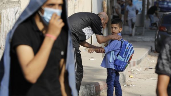 A Palestinian father picks up his son from a school run by the United Nations Relief and Works Agency (UNRWA) in Gaza City on August 13, 2020. MOHAMMED ABED / AFP