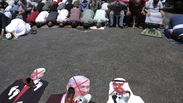Palestinians perform take part in the Friday prayers in front of cut-outs showing the faces of (L to R) Israeli Prime Minister Benjamin Netanyahu, Abu Dhabi Crown Prince Sheikh Mohammed bin Zayed al-Nahyan, and US President Donald Trump, during a demonstration in Nablus in the occupied West Bank on August 14, 2020 against a US-brokered deal between Israel and the UAE to normalise relations. The deal marks only the third such accord the Jewish state has struck with an Arab nation, an historic shift making th
