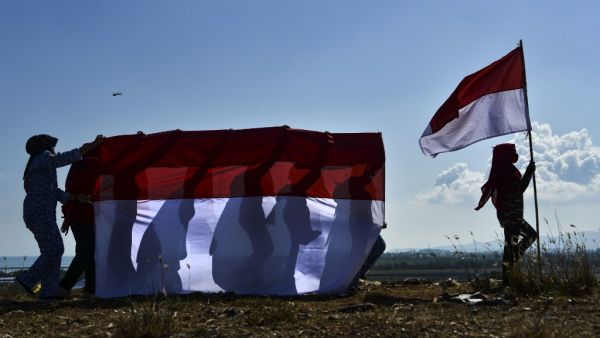 The youth of state defense carry Indonesian flags to commemorate 75th Indonesia's Independence Day which falls on August 17, at a mountain of garbage in Banda Aceh on August 16, 2020. CHAIDEER MAHYUDDIN / AFP