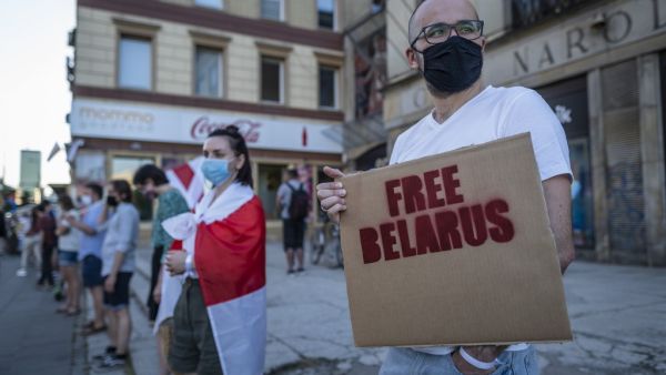 Belarus citizens in Poland hold banners and historical belarusian flags as they stand in a human chain to show solidarity with protesters in Minsk, in Warsaw on August 16, 2020. Wojtek RADWANSKI / AFP