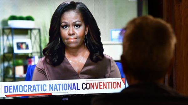 A person watches former First Lady Michelle Obama speak during the opening night of the Democratic National Convention, being held virtually amid the novel coronavirus pandemic, in Los Angeles, on August 17, 2020. America's political convention season begins tonight with former first lady Michelle Obama addressing the Democrats' now-virtual gathering set to anoint Joe Biden, as President Donald Trump defies coronavirus concerns to rally supporters in battleground Wisconsin. Chris Delmas / AFP