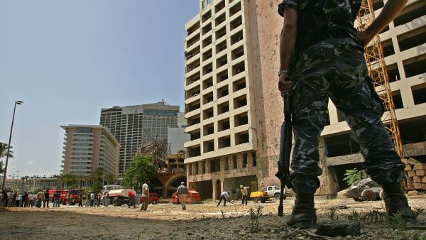 This file photo taken on May 31, 2007 shows a Lebanese policeman securing the site as municipality employees work on closing a crater at the site where a massive car bomb explosion killed former prime minister Rafiq Hariri in Beirut on February 14, 2005. The special tribunal trying the four suspects accused of the 2005 assassination of Lebanon's former prime minister Rafic Hariri is expected to deliver its verdict on on August 18, 2020.  MARWAN NAAMANI / AFP
