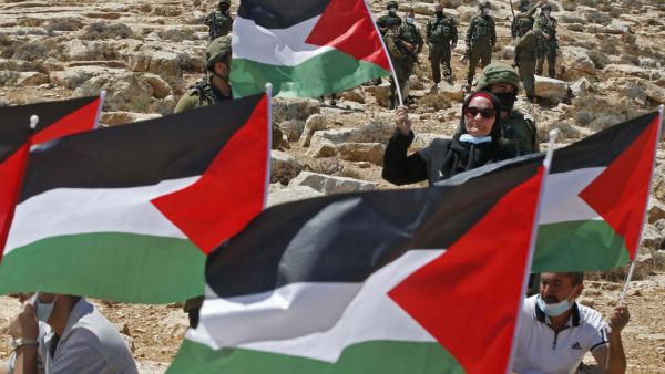 Palestinian landowners and demonstrators lift national flags as they protest Israeli settlement building activities on their land in Al-Thaalaba village, near Yatta in area (C), south of Hebron city in the occupied West Bank, on August 21, 2020. "Area C" is a stretch of land accounting for 60 percent of the West Bank over which Israel has control under the terms of the Oslo Accords signed between Israel and the Palestinians in the 1990s. It is extremely difficult for Palestinians to receive building permits