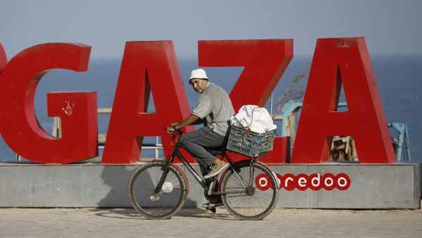 A Palestinian man rides a bicycle on the Gaza beachfront early on August 25, 2020, as a 48-hour total lockdown is declared in the Strip following the discovery of local cases of the novel coronavirus. MOHAMMED ABED / AFP