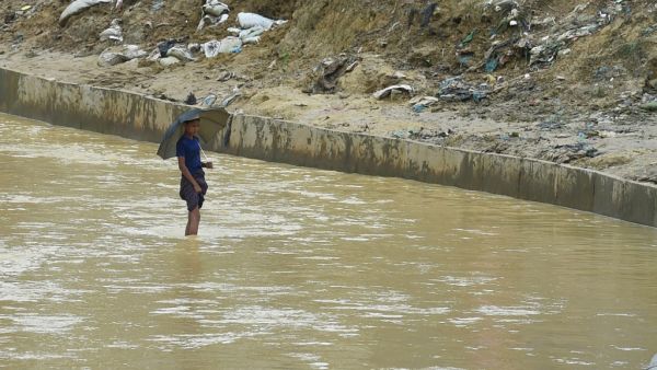 A Rohingya refugee stands in the waters of a canal at Kutupalong refugee camp near Ukhia on August 25, 2020. Almost a million Rohingya refugees stuck in Bangladesh marked three years since escaping from Myanmar on August 25, with coronavirus forcing them to hold a day-long "silent protest" inside their flimsy, leaky huts. Munir Uz zaman / AFP